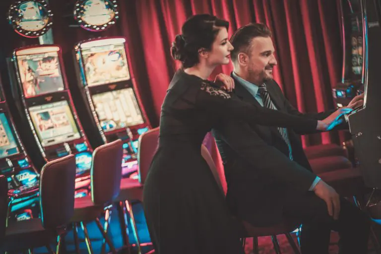 Two people in front of slot machines.