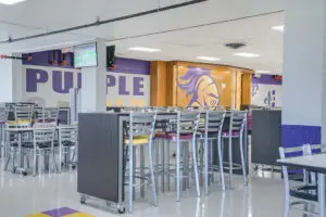 High School cafeteria with mascot murals and furniture in school colors, yellow and purple.