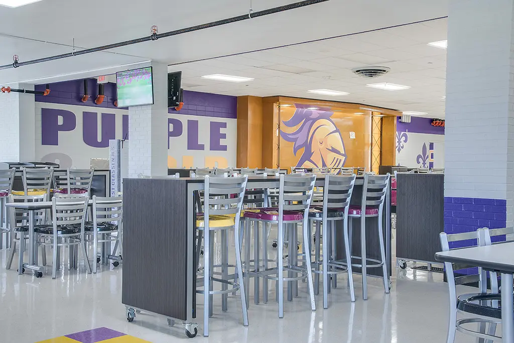 High School cafeteria with mascot murals and furniture in school colors, yellow and purple.